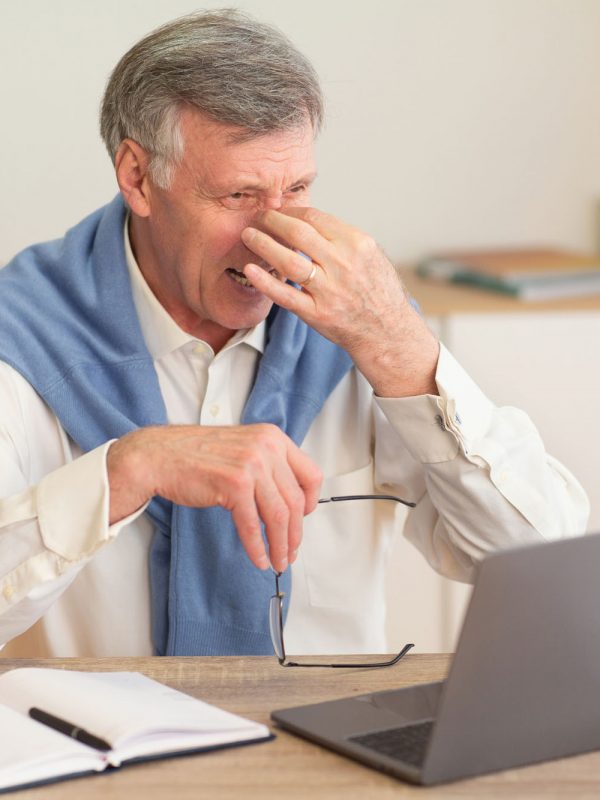 Eyestrain Concept. Elderly Businessman At Laptop Massaging Nosebridge Having Headache Or Sore Eyes Sitting In Modern Office. Selective Focus